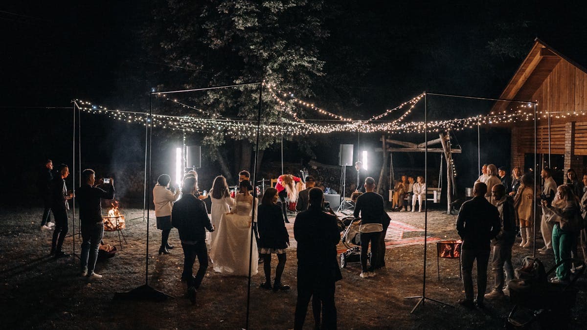 Outdoor evening wedding reception under string lights, capturing the romantic ambiance of an al fresco dinner setting